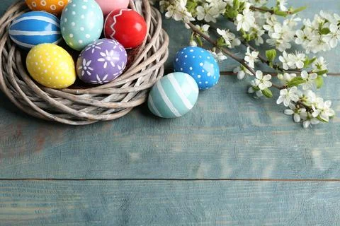 Painted Easter eggs in nest and blossoming branches on table, view from above Stock Photos