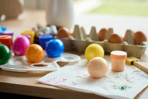 Painted Easter eggs with paints and palette on wooden table Stock Photos