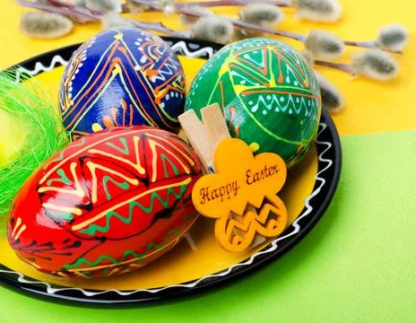 Painted Easter eggs on a plate against the background of willow branches. Stock Photos