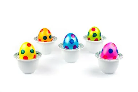 Painted easter eggs standing in porcelain egg cups on white Stock Photos