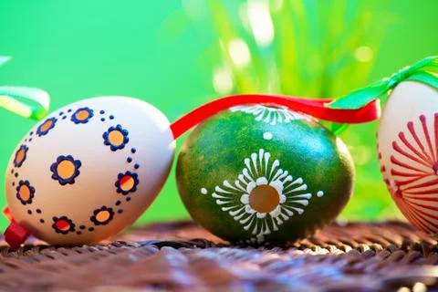Painted easter eggs in the wicker basket in the grass. Stock Photos