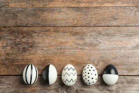 Painted Easter eggs on wooden background, flat lay with space for text Stock Photos