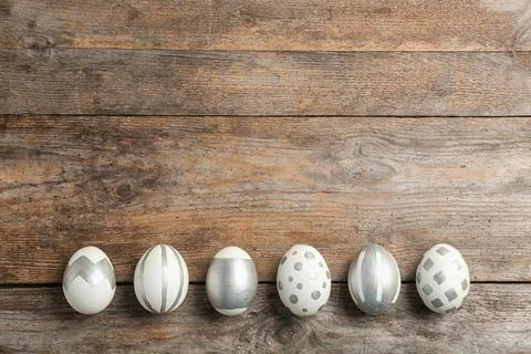 Painted Easter eggs on wooden background, flat lay with space for text Stock Photos