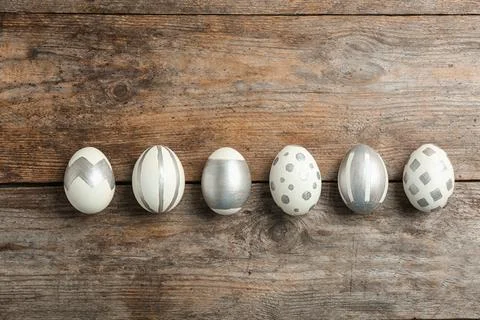 Painted Easter eggs on wooden background, flat lay Stock Photos