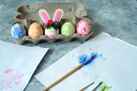 Painted eggs and one egg decorated with bunny ears, diy easter eggs concept Stock Photos