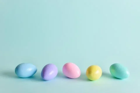 Painted eggs of delicate tones lie on a pale blue background. Stock Photos