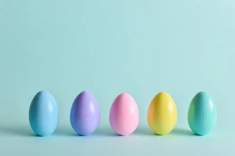 Painted eggs of delicate tones stand on a pale blue background. Stock Photos