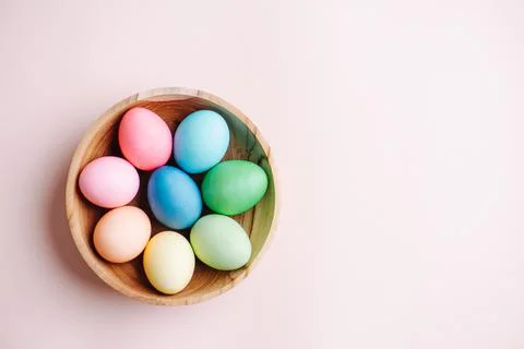 Painted multi-colored easter eggs in a wooden bowl. Top view. Stock Photos