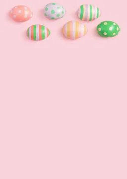 Painted multi-colored Easter eggs lie at the top of the pink background Stock Photos