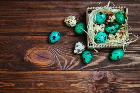Painted quail eggs in the box over wooden background Stock Photos