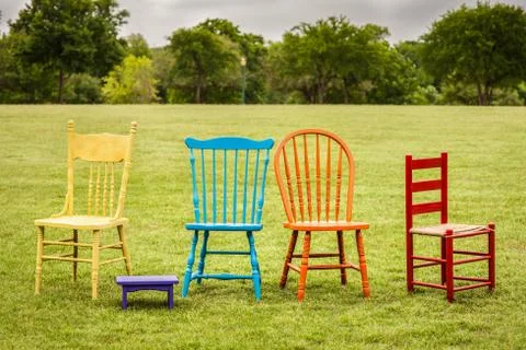 Painted spring colored chairs in an open field Stock Photos