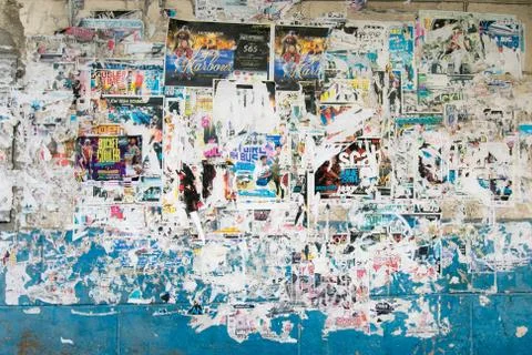 Painted wall covered with layers of old torn out posters and flyers. Stock-Fotos