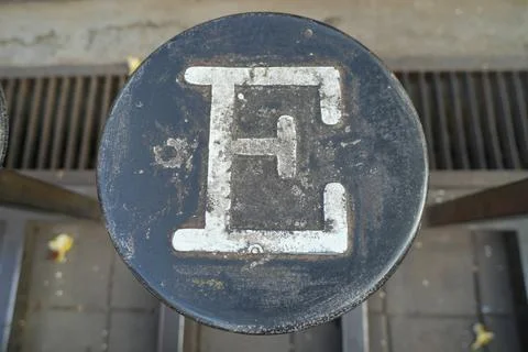 A painted white letter E on a round black metal. Stock Photos