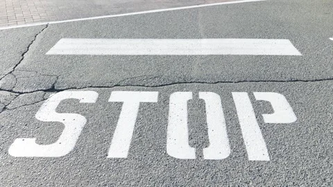 Painted white stop sign and limit line on cracked asphalt road 库存影片 338177420