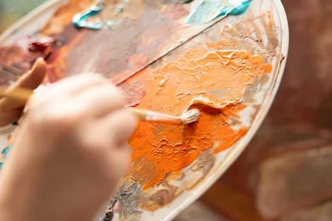 Painter applying orange acrylic texture on canvas Stock Photos