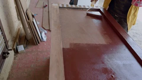 Painter applying red paint primer on a wood cabinet furniture on carpenter .. Stock Footage 264619704
