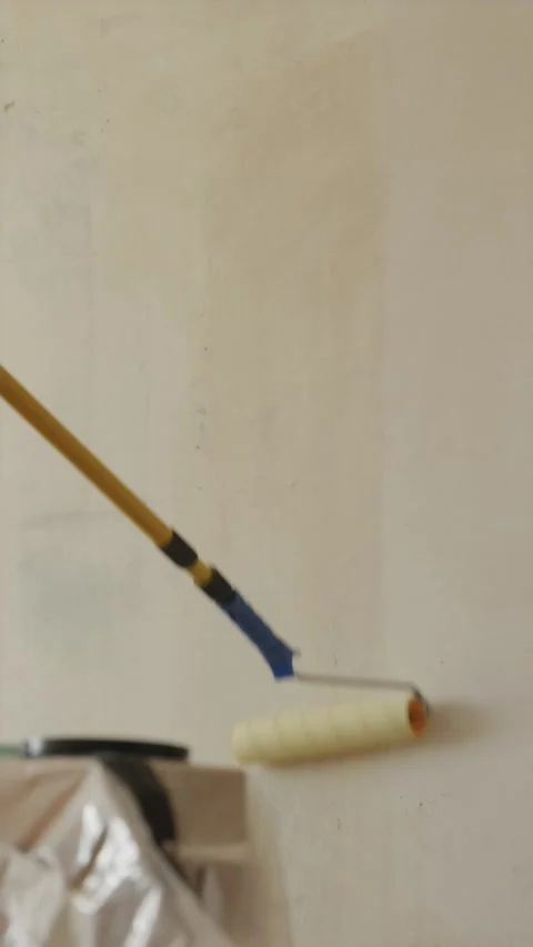 Painter applying wet primer coat to wall with roller full shot Stock Footage 340404969