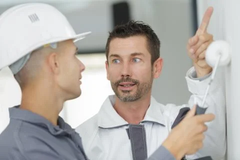 Painter with apprentice using roller on wall Stock Photos