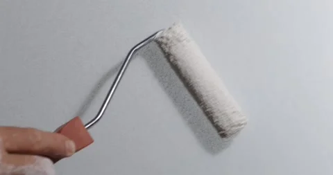 Painter coats wall using handheld paint roller for simple DIY decorating up.. Stock Footage 348444819