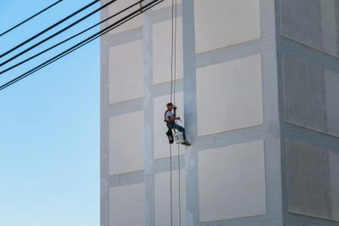 Painter coming down the facade of a building rappelling with a rope Fotos de archivo