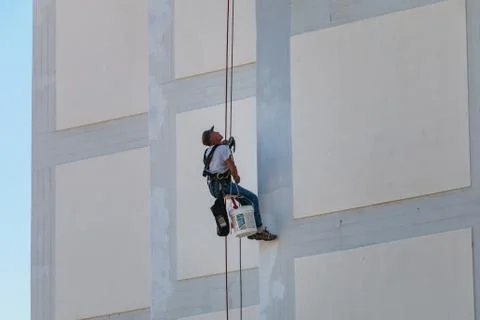 Painter coming down the facade of a building rappelling with a rope Fotos de archivo