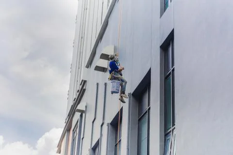 Painter coming down the facade of a building tower rappelling with a rope. Fotos de archivo