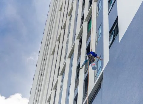 Painter coming down the facade of a building tower rappelling with a rope. Fotos de archivo