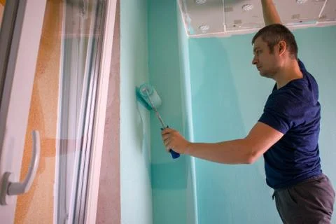 Painter covers the walls with paint. Master works as a painting roller in the Stock Photos
