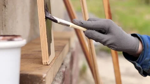 Painter covers a wooden panel with brown varnish Video stock 334026815