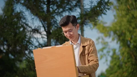 Painter creating in nature setting. Artist focused on painting in lush park Stock Footage 329793016