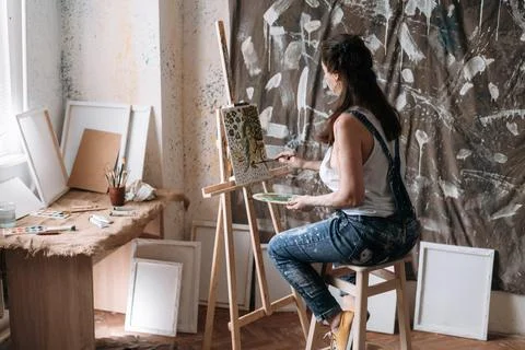 Painter in creative art studio with brush and palette creating artwork on e.. Stock Photos