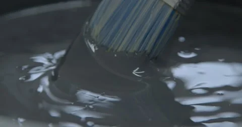 Painter dips brush into thick grey paint reflecting light 스톡 동영상 169631548
