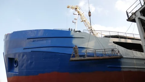 The painter in the dry dock paints the ship in blue. Stock Footage 87085452