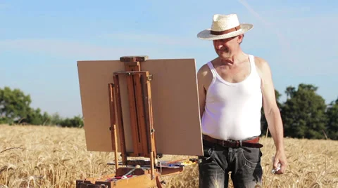 Painter with an easel in the middle of a wheat field 스톡 동영상 28323107