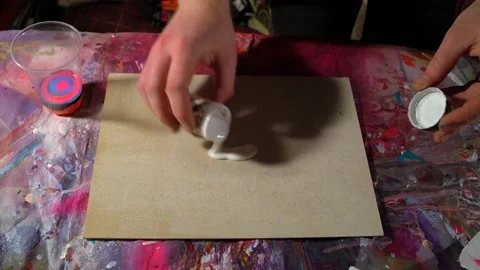 Painter in fluid art style preparing canvas for painting by pouring white paint Video stock 154435443
