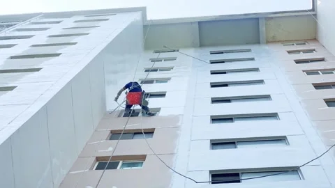 A painter hanging from a tall building Stock Footage 311575876