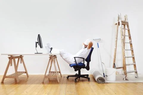 Painter man after work rests with feet on the desk, weekend concept Stock Photos