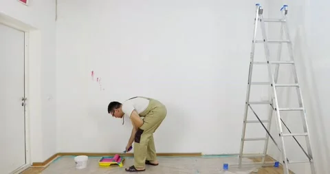 Painter man dips roller into a plastic pallet with pink paint. Stock Footage 154718954