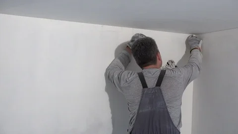 Painter man grinds wall. Handyman aligns walls with sandpaper Stock Footage 105270425