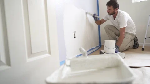 Painter man painting the wall in home, with paintbrush and white color, 4k Stock Footage 129140904