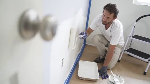 Painter man painting the wall in home, with paint roller and white color, 4k Stock Footage 129140996