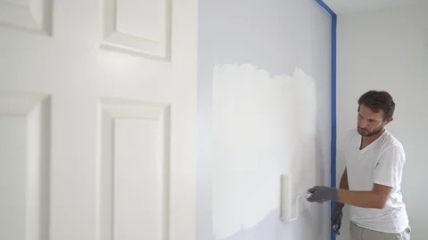 Painter man painting the wall in home, with paint roller and white color, 4k Stock Footage 129141082