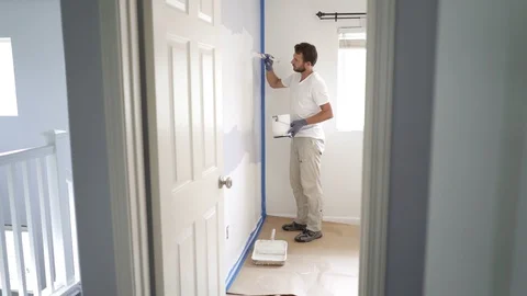 Painter man painting the wall in home, with paintbrush and white color paint. 4k Stock Footage 129141092