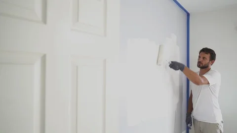 Painter man painting the wall in home, with paint roller and white color, 4k Stock Footage 129141183