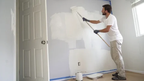 Painter man painting the wall in home, with paint roller and white color, 4k Stock Footage 129141277