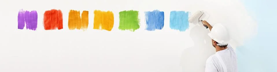 Painter man with roller paint drawing color samples on white blank wall backg Foto stock
