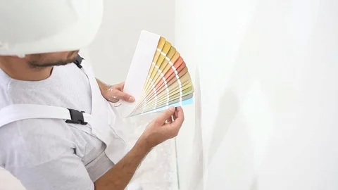 Painter man at work choice color with swatches samples, wall painting concept Stock Footage 88256433