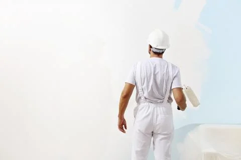 Painter man at work with a paint roller, wall painting concept Stock Photos