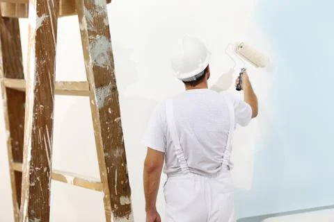 Painter man at work with a paint roller, wall painting concept Stock Photos