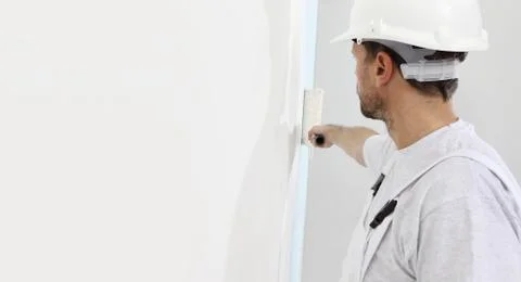 Painter man at work with a paint roller, wall painting concept Stock Photos